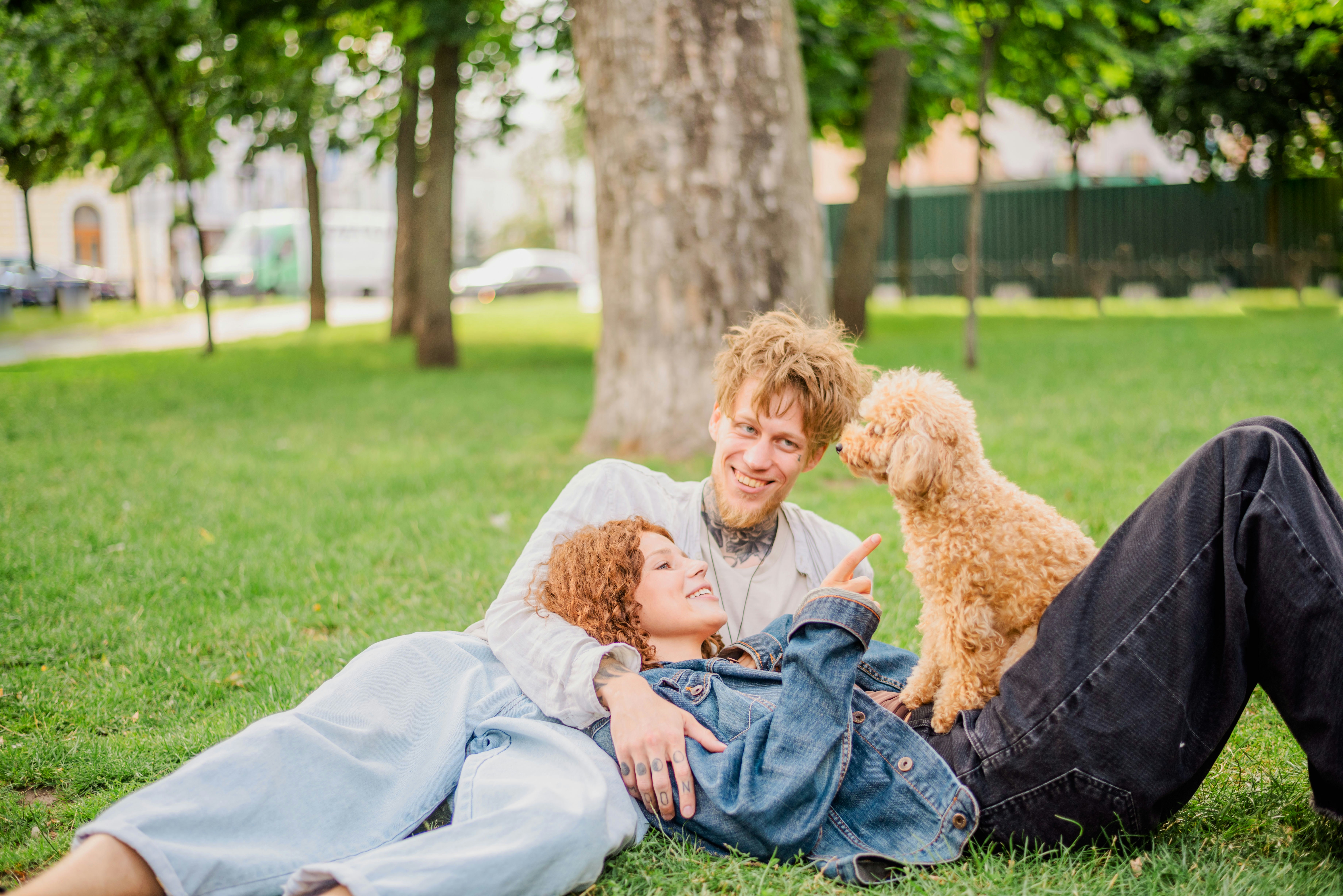 A man and woman laying in the grass with a dog photo – Free Grass Image ...