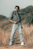 a man standing in a field with his hands in his pockets