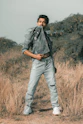 a man standing in a field with his hands in his pockets