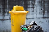 A bright yellow skip bin loaded with garden waste outside a suburban home.