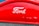 A red car grille showcasing the Ford logo in white, with a metallic mesh below it.