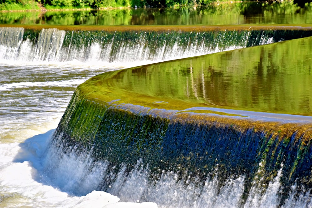 a water fall with green and yellow algae growing on it