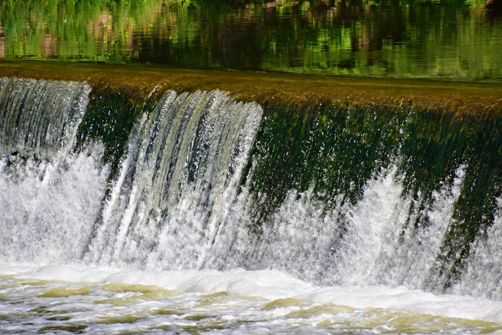 a man riding a surfboard on top of a waterfall