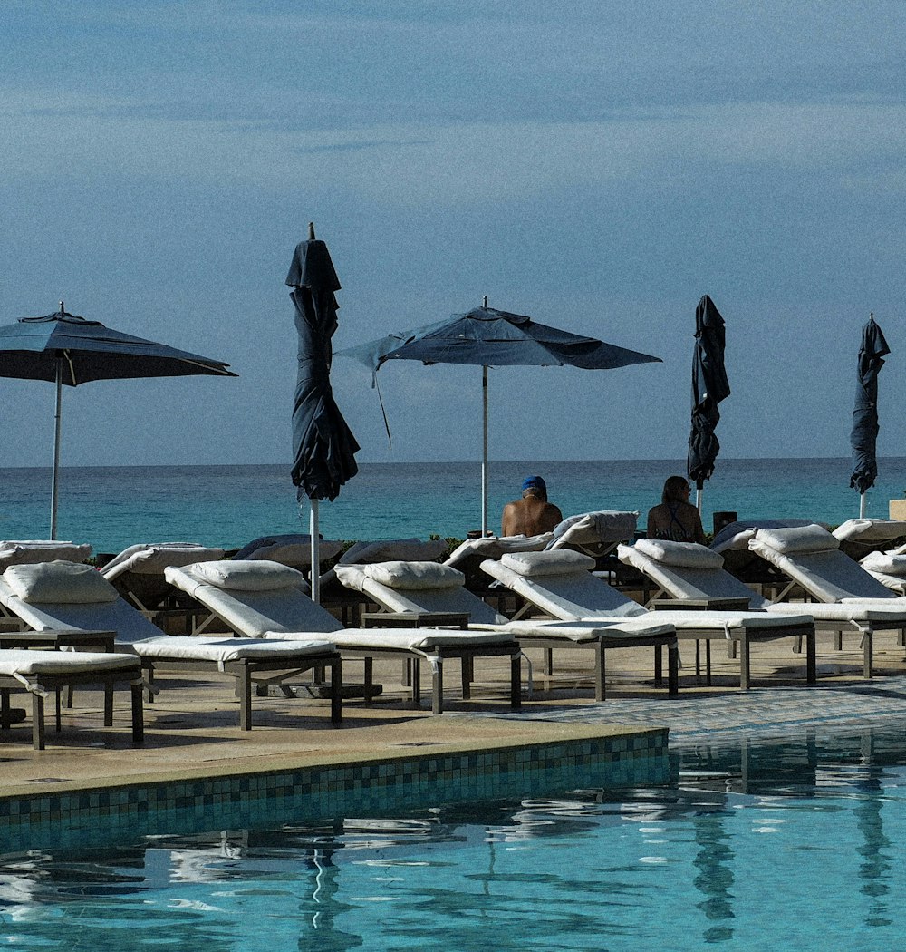 a row of lounge chairs sitting next to a swimming pool