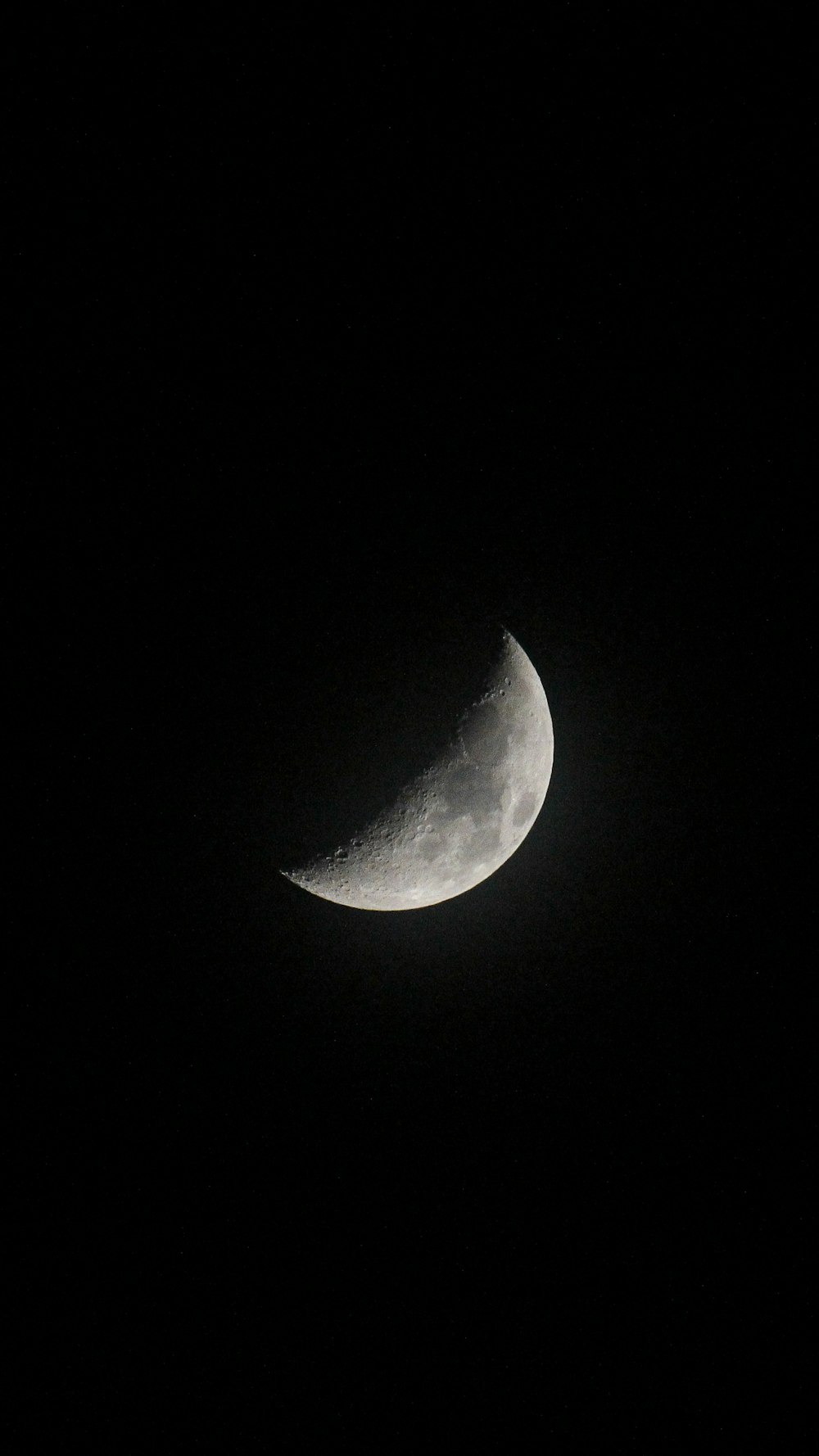 a half moon is seen in the dark sky