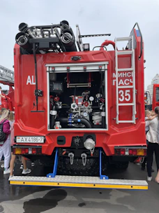 A bright red firetruck with ladders and hoses, staged on a studio lot.