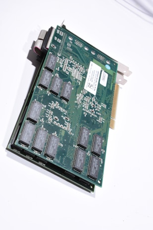 A close-up view of an electronic circuit board featuring various electronic components such as integrated circuits and connectors, mounted on a green printed circuit board. The board has a metallic bracket on one end for mounting in a computer case, and a gold-plated edge connector for interfacing with a computer motherboard.