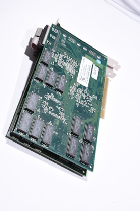 A close-up view of an electronic circuit board featuring various electronic components such as integrated circuits and connectors, mounted on a green printed circuit board. The board has a metallic bracket on one end for mounting in a computer case, and a gold-plated edge connector for interfacing with a computer motherboard.