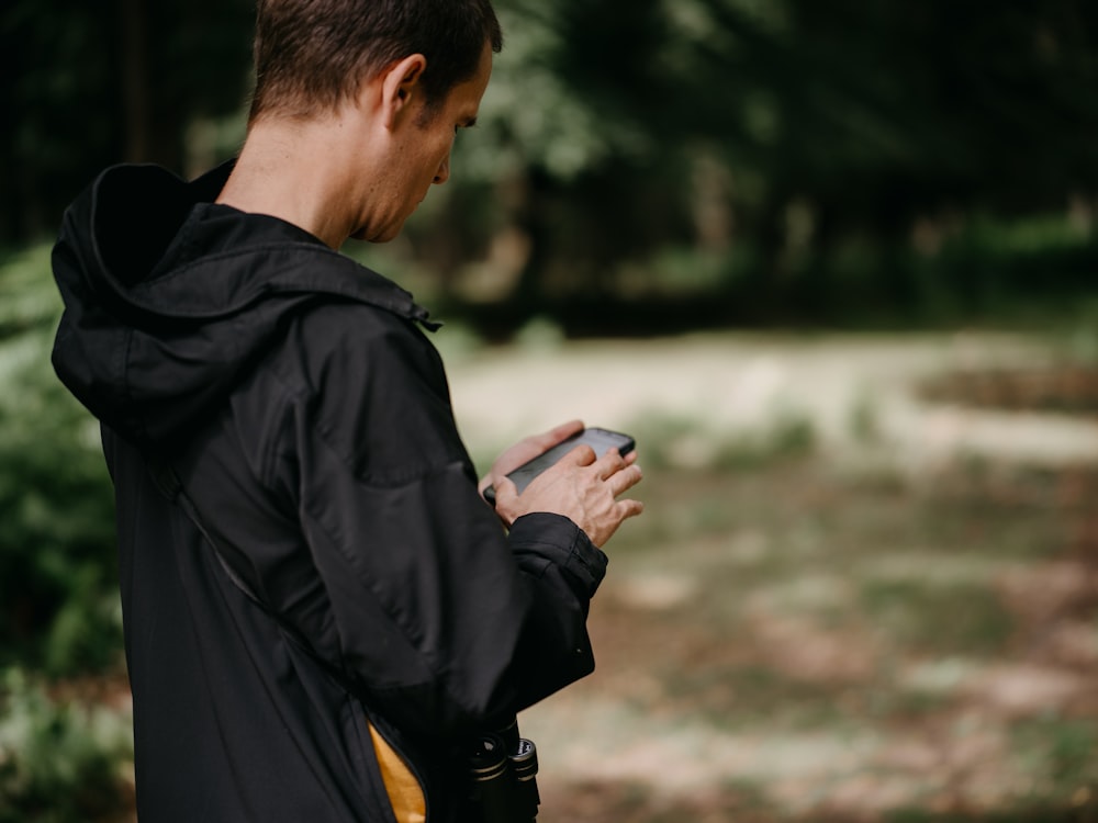 a man standing in the woods looking at his cell phone