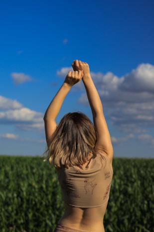 A close-up photo of a woman stretching her arms outside on a sunny day, symbolizing freedom from pain.