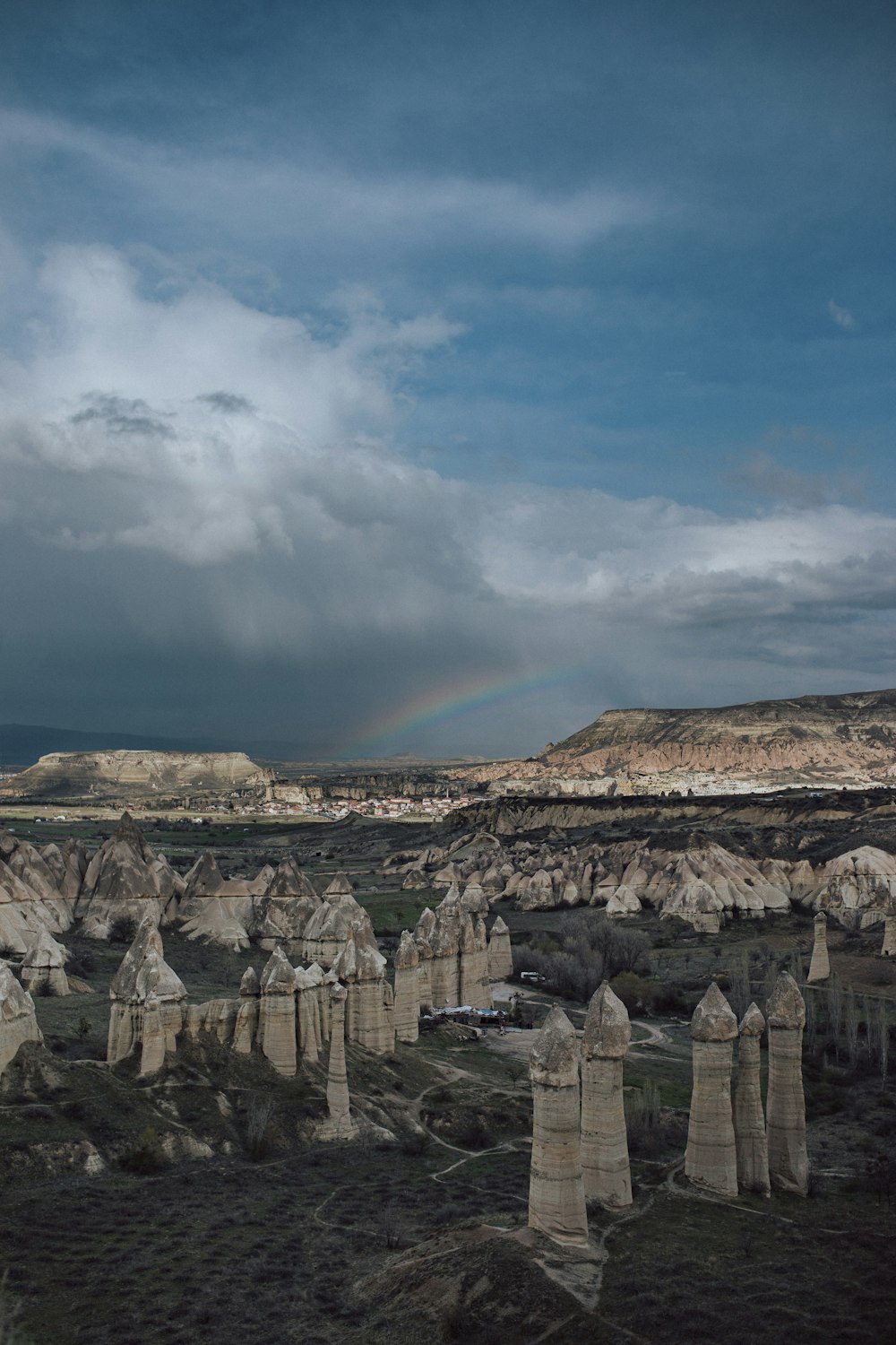 a rainbow shines in the sky over a rocky landscape