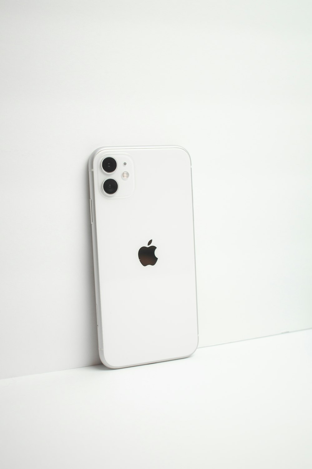 a white iphone sitting next to a white wall