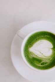 Close-up of a vibrant green royal matcha latte with frothy top in a sleek ceramic cup.