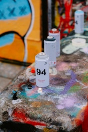 a group of cans sitting on top of a table covered in graffiti