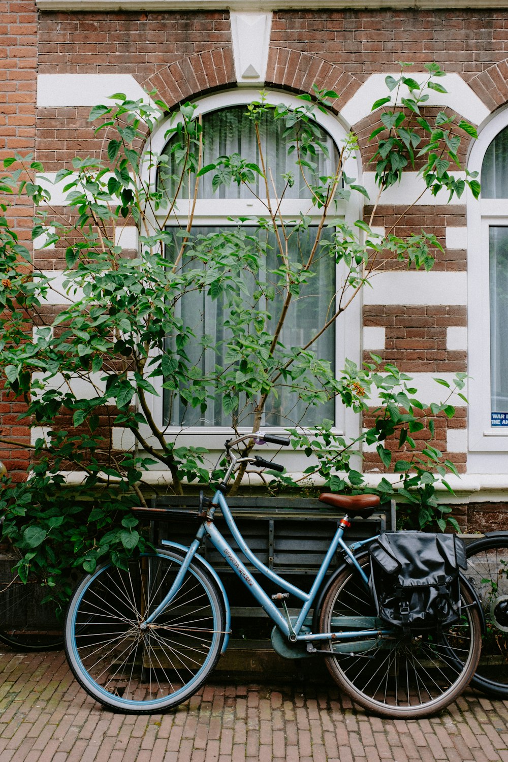 a blue bicycle parked next to a window