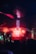 A vibrant club scene with colorful lighting effects, featuring a crowd of people with raised hands silhouetted against the bright lights. Smoky red and blue hues dominate the atmosphere as beams of light create a dynamic and energetic environment.