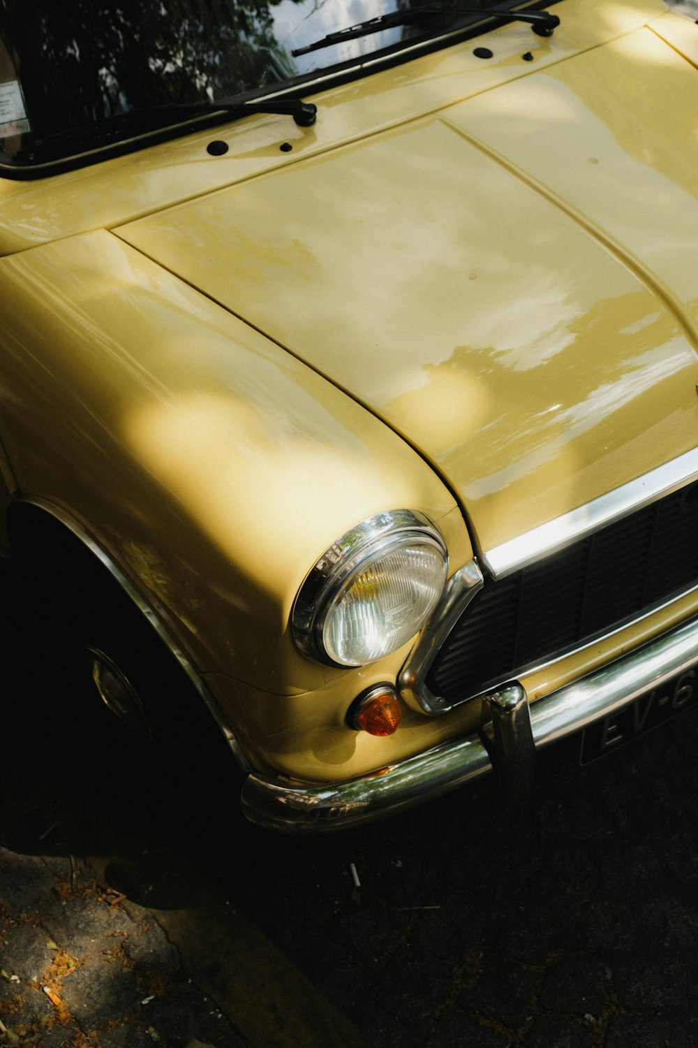 an old yellow car parked on the side of the road