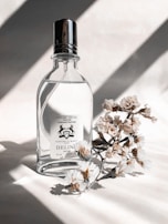 A delicate perfume bottle catching light on a marble countertop with fresh flowers nearby.