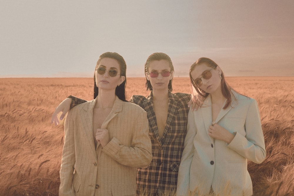 three women standing in a field of wheat