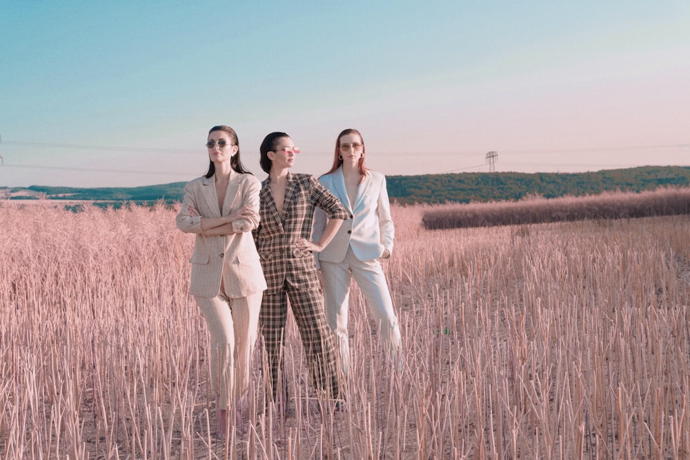 three women standing in a field of tall grass