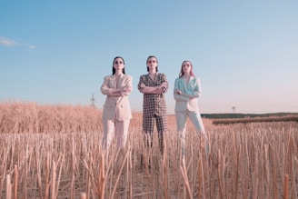 a group of three women standing in a field