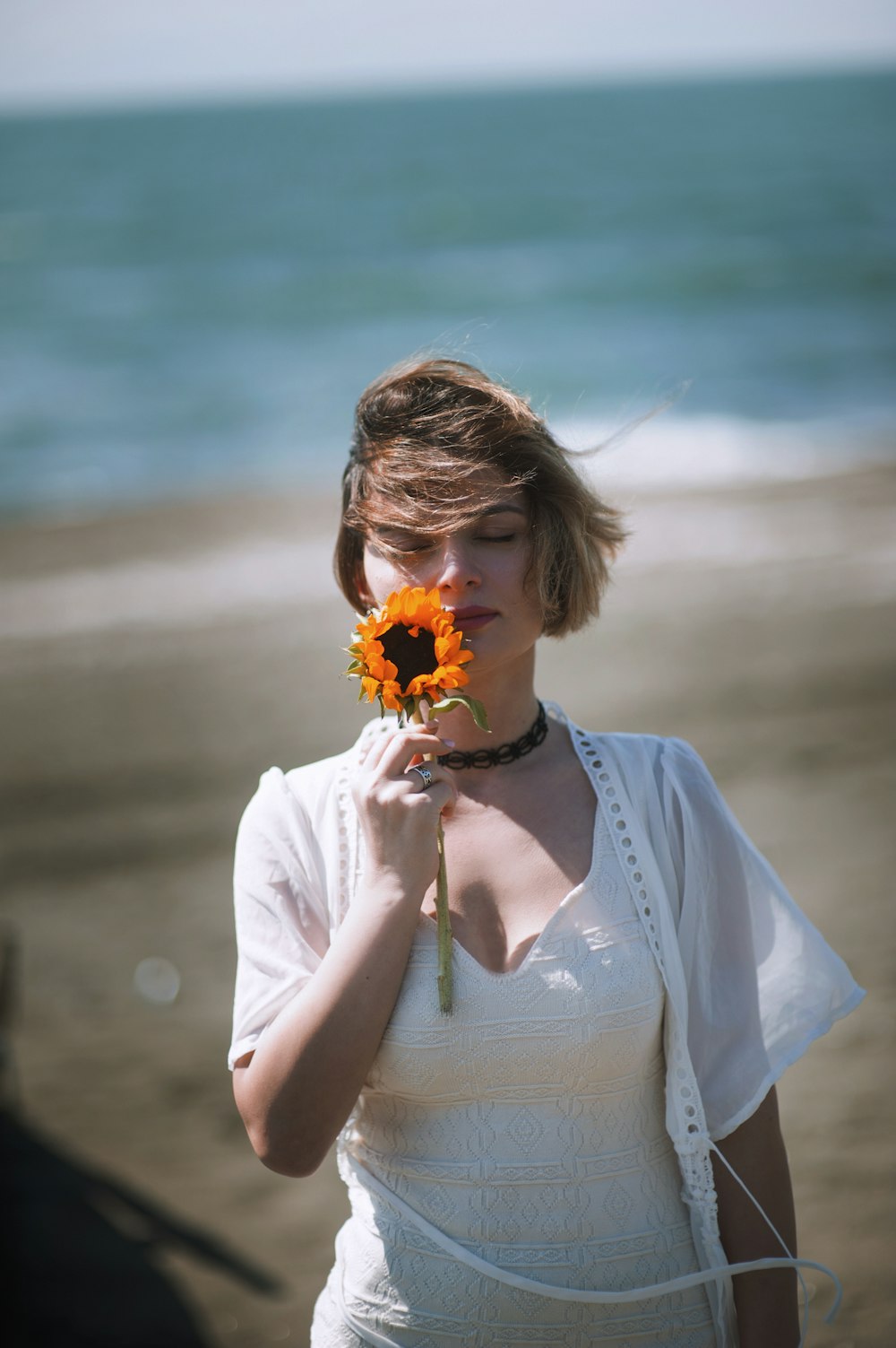 uma mulher em pé em uma praia segurando uma flor