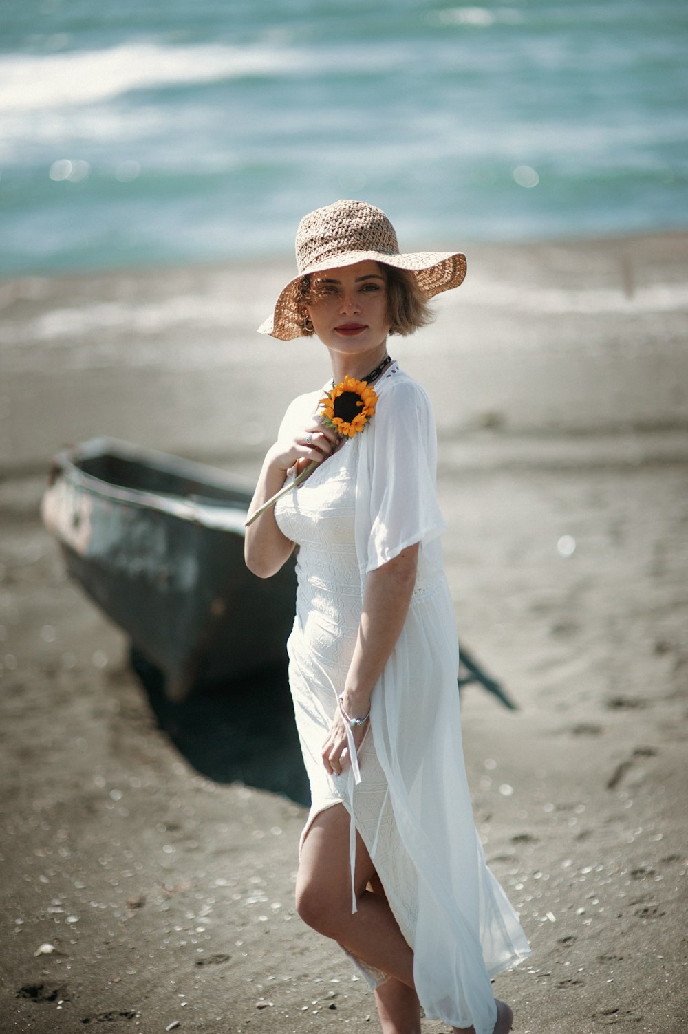 uma mulher em pé em uma praia ao lado de um barco