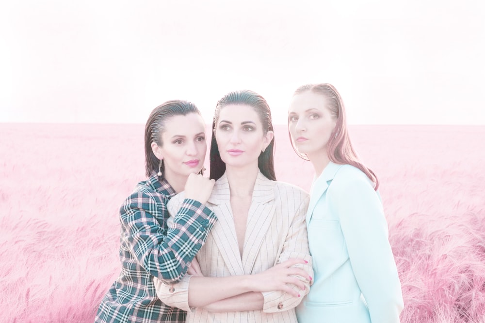 three women standing in a field of pink grass