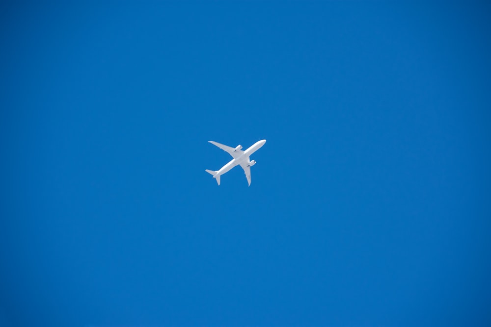 ein weißes Flugzeug, das in einem blauen Himmel fliegt