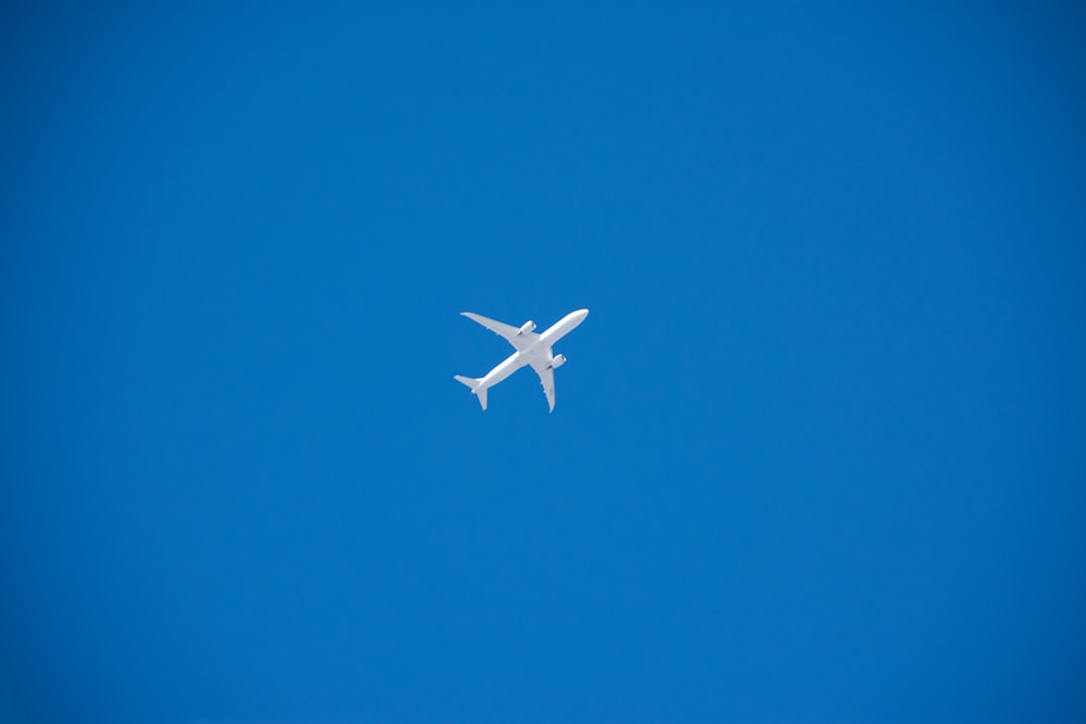 a white airplane flying in a blue sky