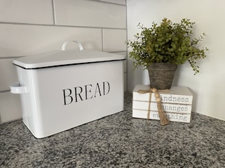 A bamboo bread box sitting on a kitchen counter with fresh bread inside.