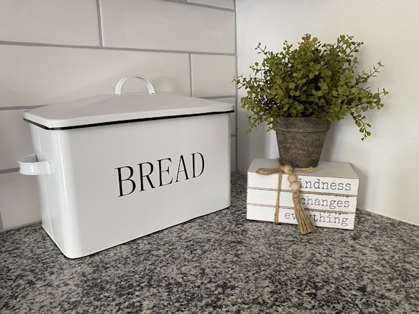 A bamboo bread box sitting on a kitchen counter with fresh bread inside.