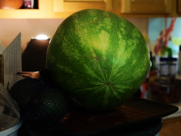 A vibrant basket overflowing with ripe, juicy watermelons on a rustic wooden table.