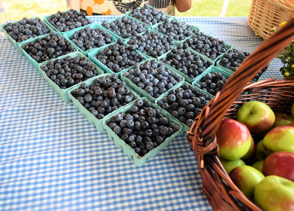 a table topped with baskets of blueberries and apples