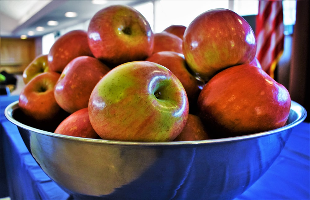 a large metal bowl filled with lots of apples