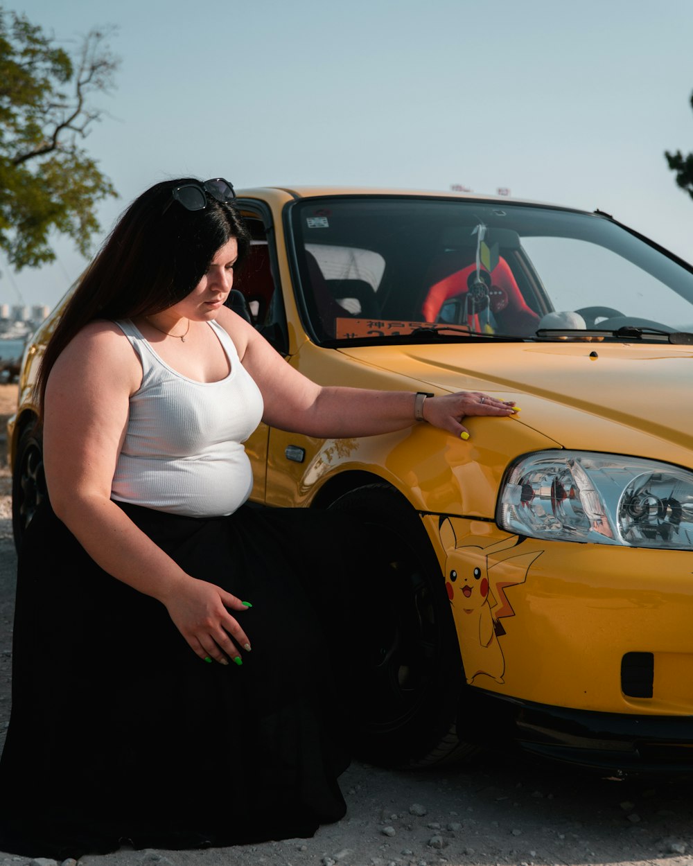 a woman sitting on the hood of a yellow car