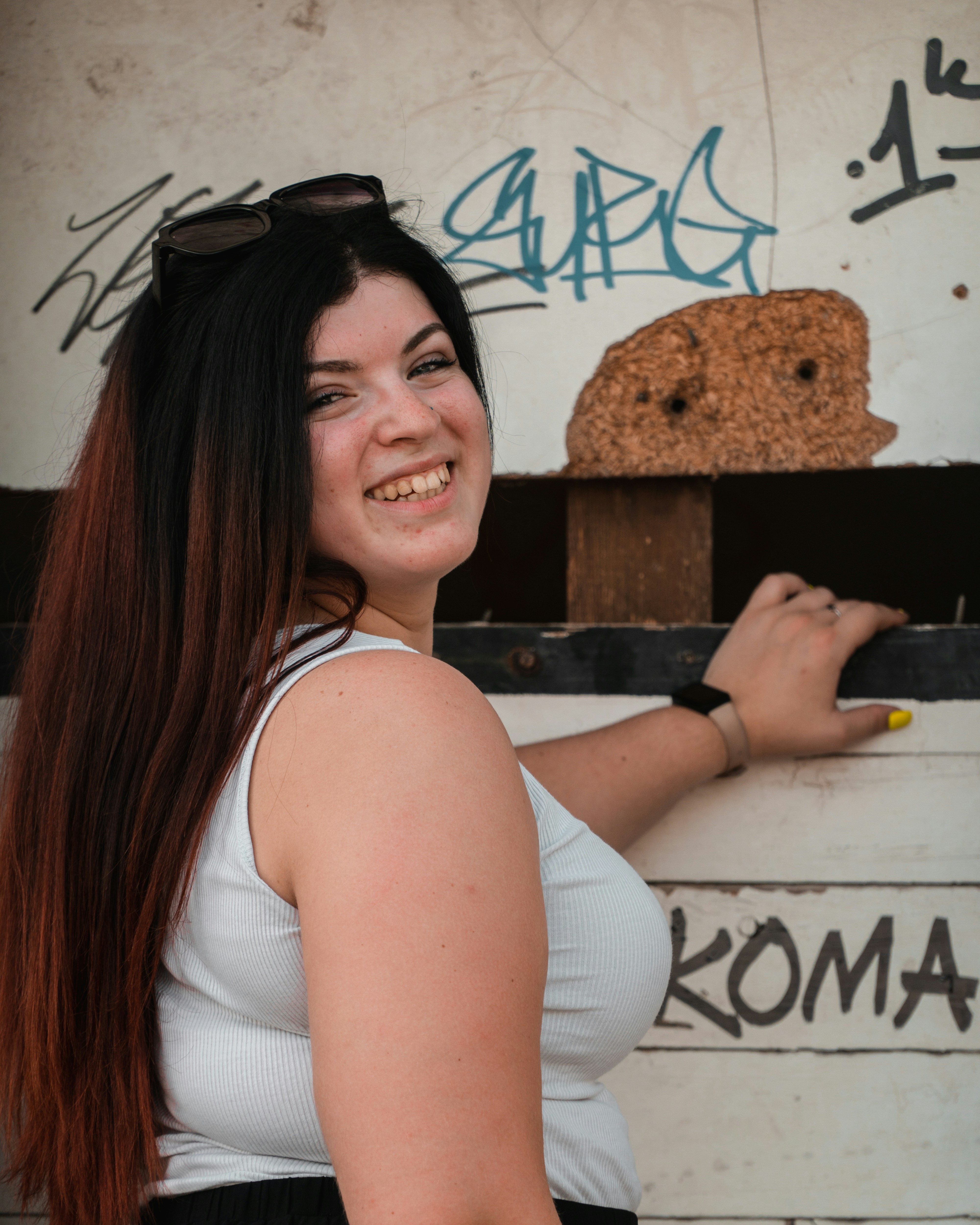 a woman with long hair and sunglasses standing in front of a wall