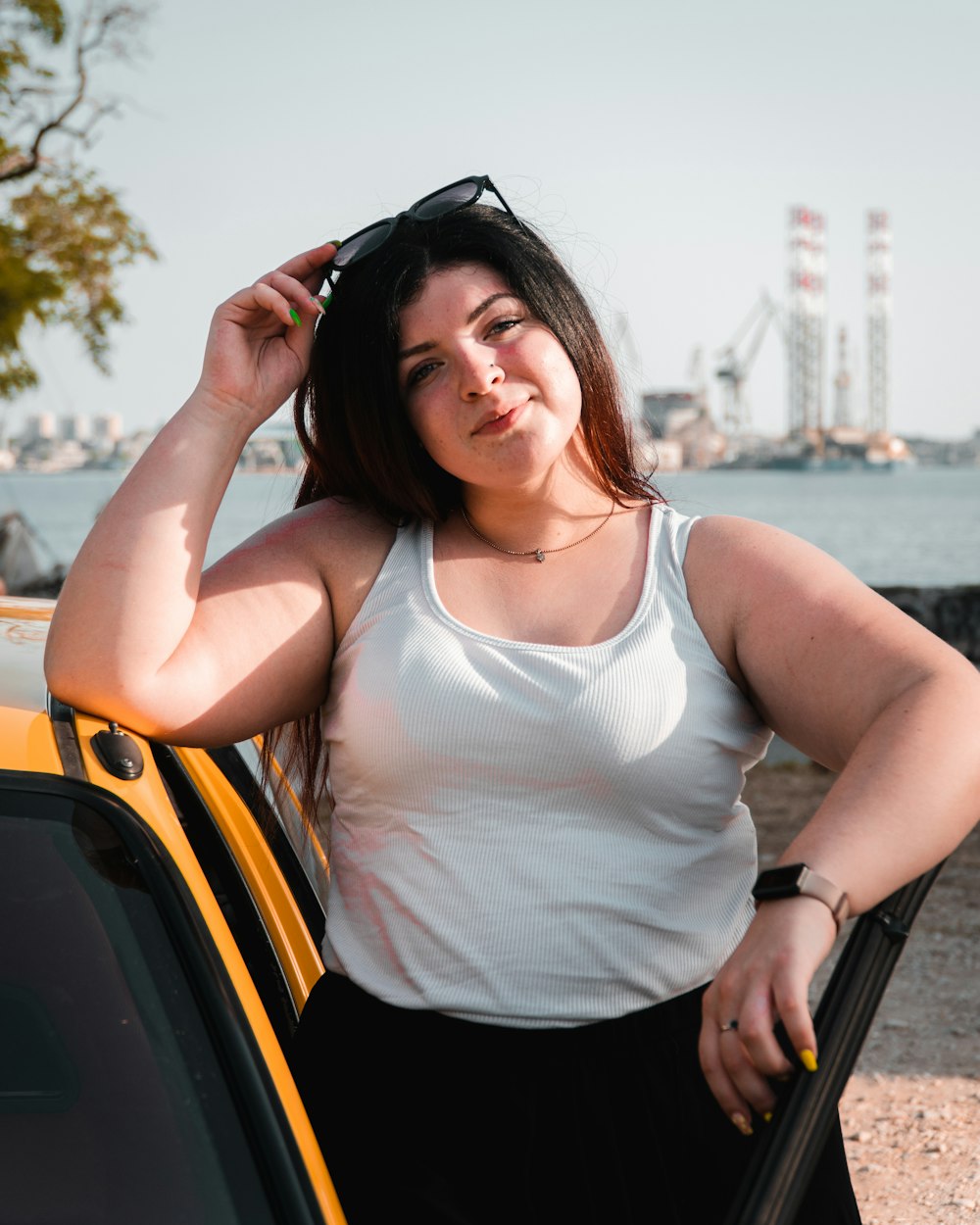 a woman leaning on a car with her hand on her head