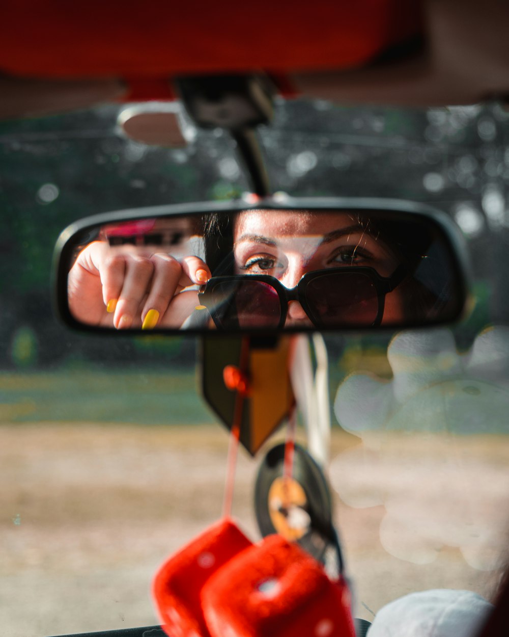 a woman taking a picture of herself in the rear view mirror of a car