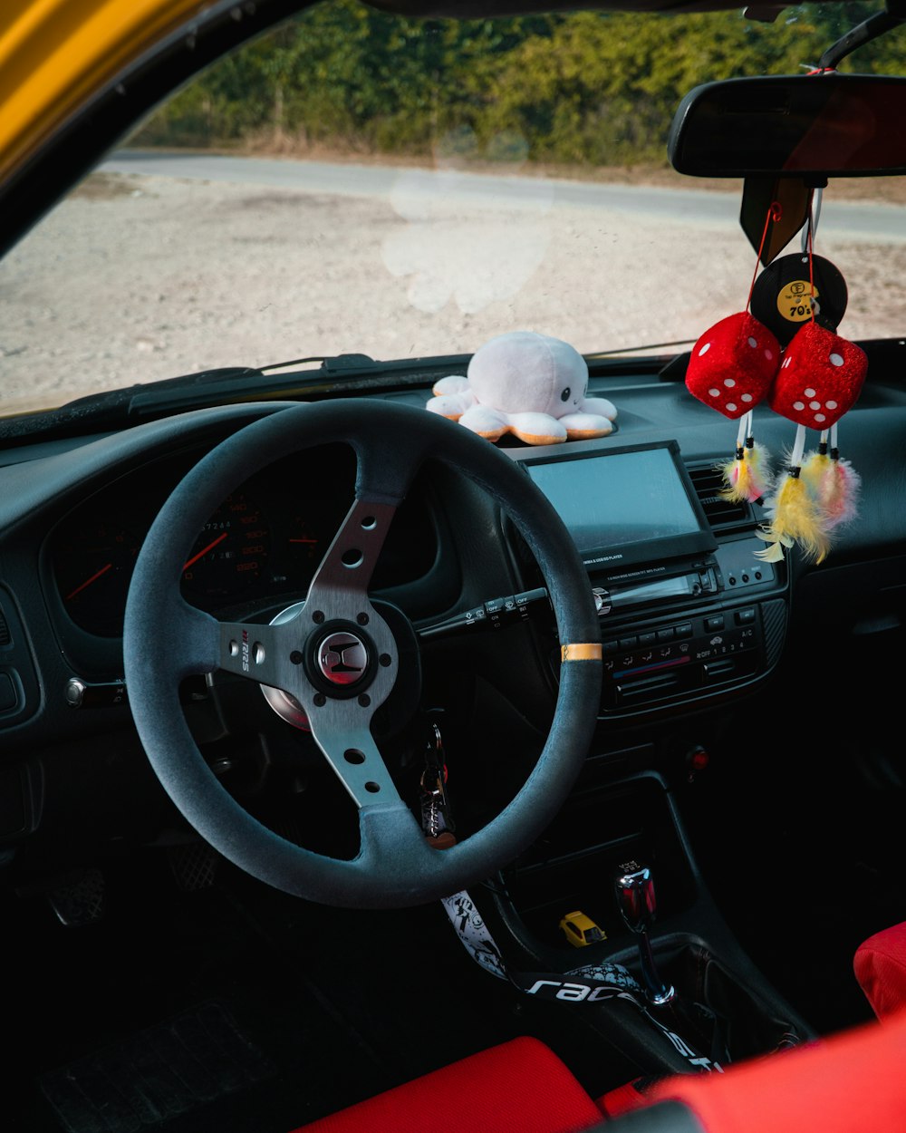 a car dashboard with a stuffed animal on the steering wheel