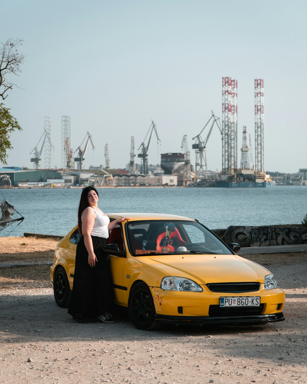 a woman standing next to a yellow car