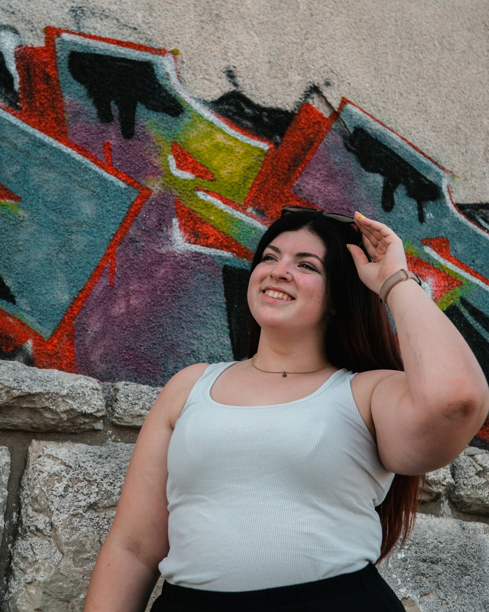 a woman standing in front of a wall with graffiti on it