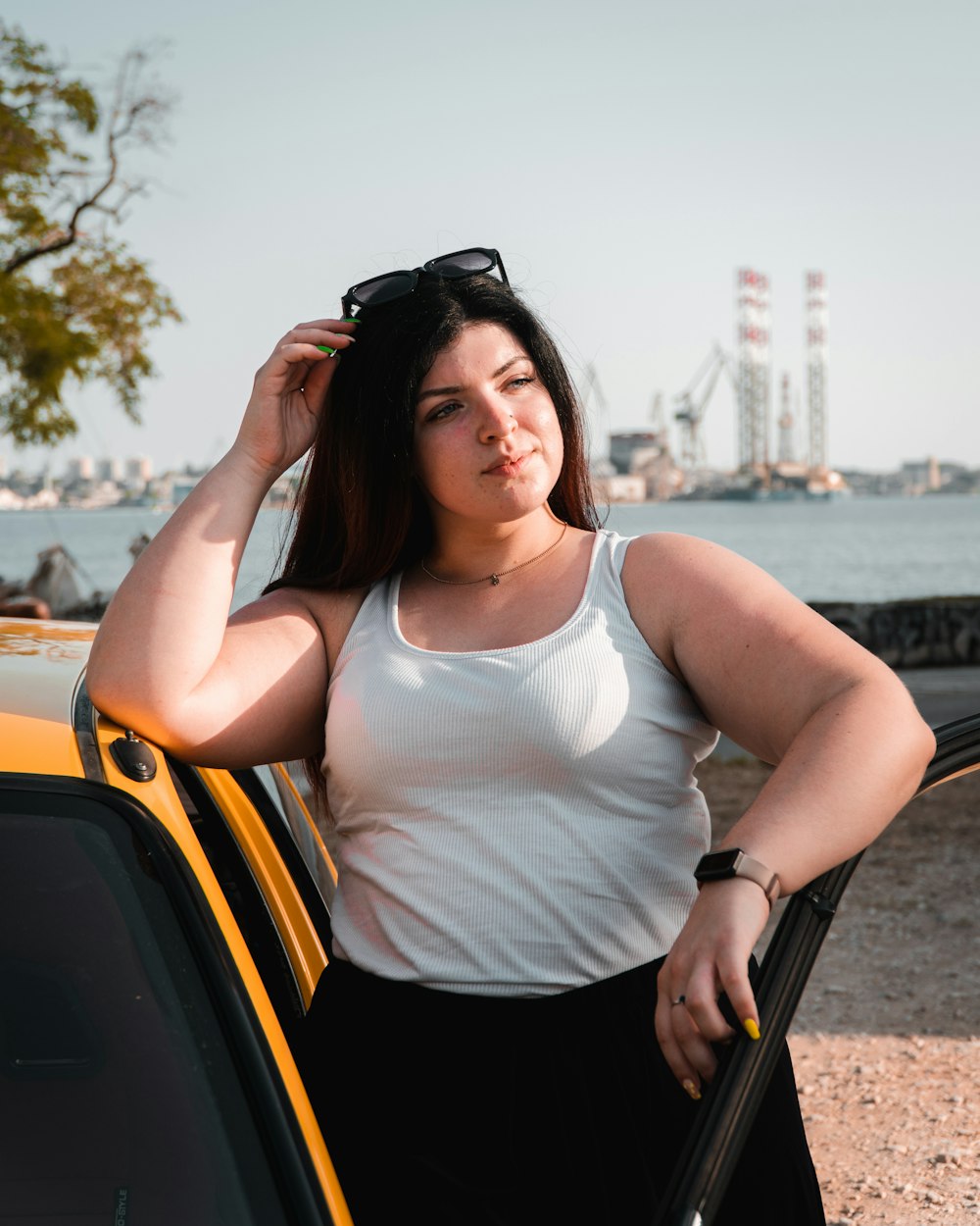 a woman leaning on a car with her hand on her head