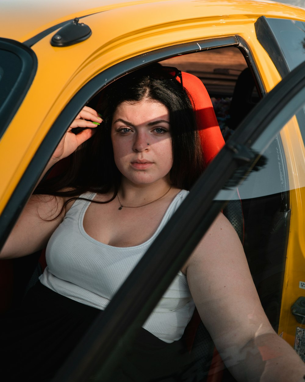 a woman sitting in a yellow car looking out the window