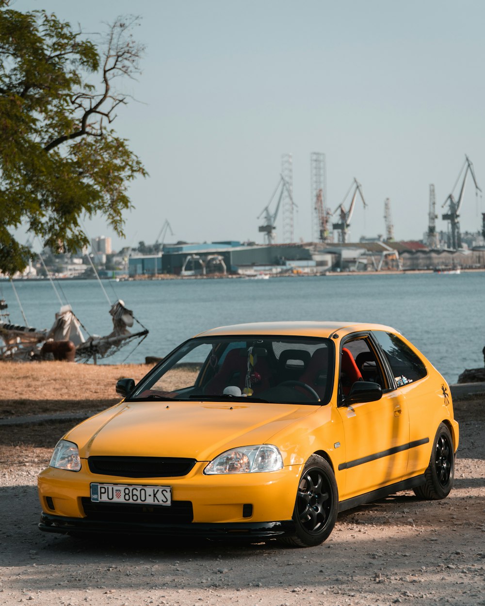 a yellow car parked in front of a body of water