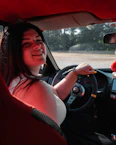 A cheerful driver handing over keys to a happy passenger outside a cozy home at night.