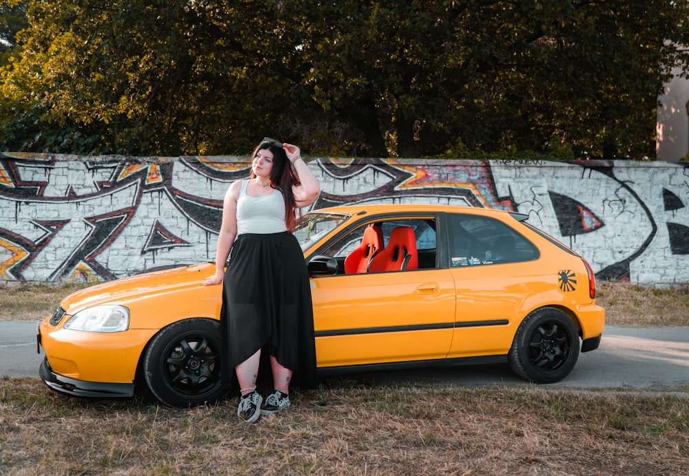 a woman standing next to a yellow car