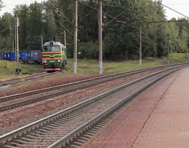 a train traveling down train tracks next to a forest