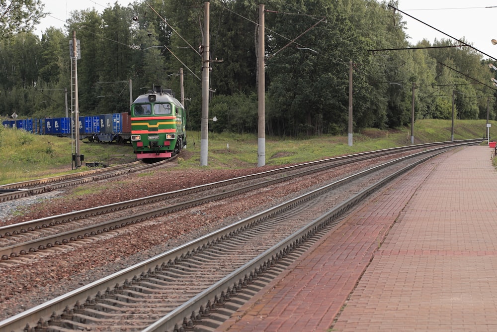 un train descendant les voies ferrées à côté d’une forêt