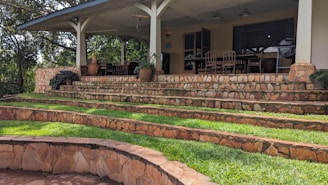 Wide view of a charming patio with matching stone steps leading up to a front porch